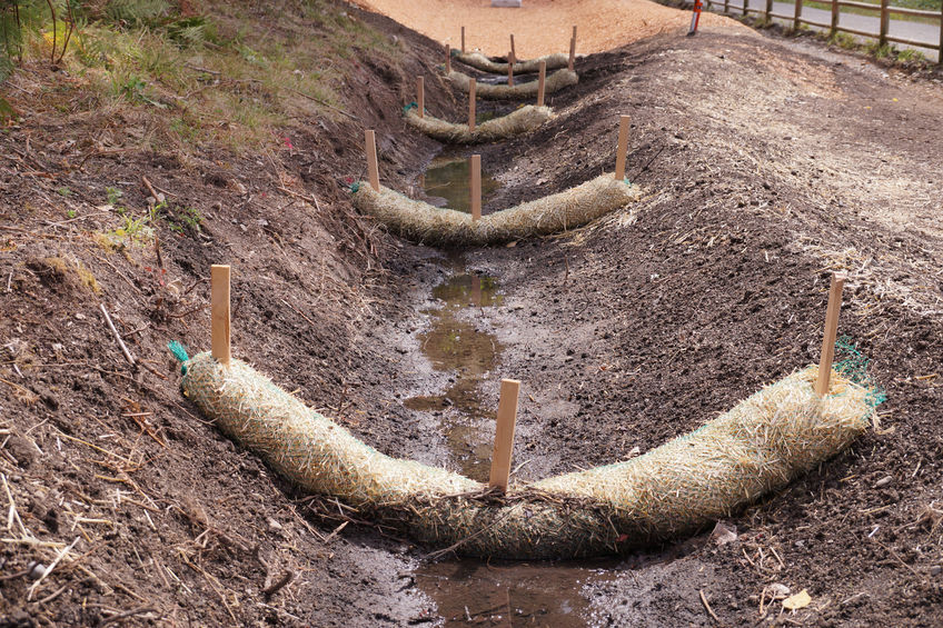 The use of straw wattles. Land drainage works. Close up of a bobcat or skid loader